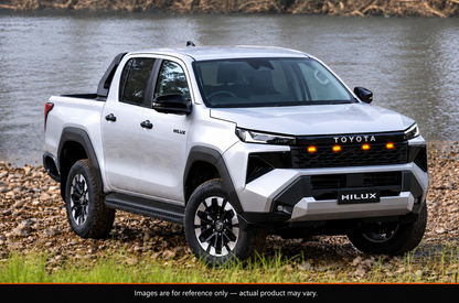 Toyota HiLux 2026 N90 with aftermarket gloss black LED grille, side angle view by the river