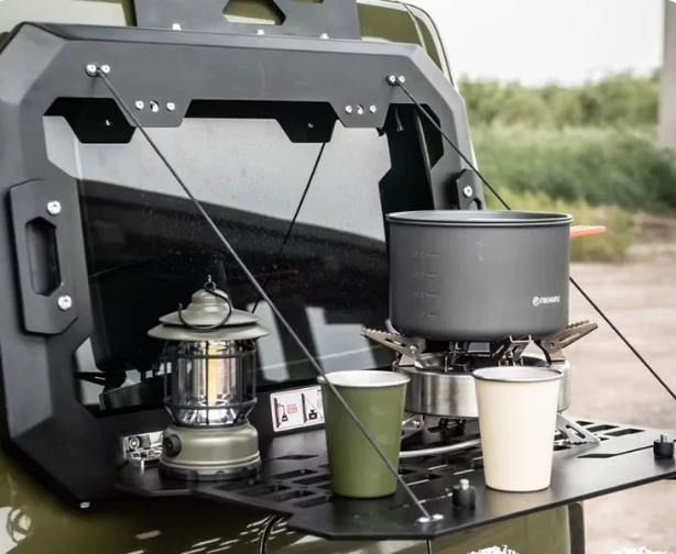 MK accessory panel fold-down table in use at a campsite with a camping stove and cups